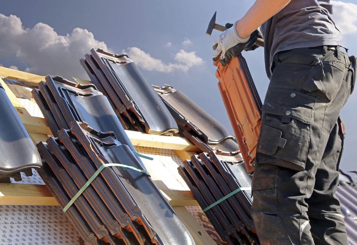 a roofer replacing a roof tile